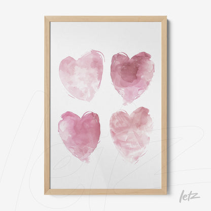 framed wall art displaying four watercolor hearts in shades of pink with a light wooden frame