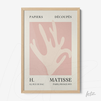 framed abstract art of a hand in pink background with light wood frame