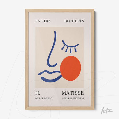 framed modern art inspired by Henri Matisse, featuring an abstract face outlined in blue with a red circle and graphic details, in a light wood frame