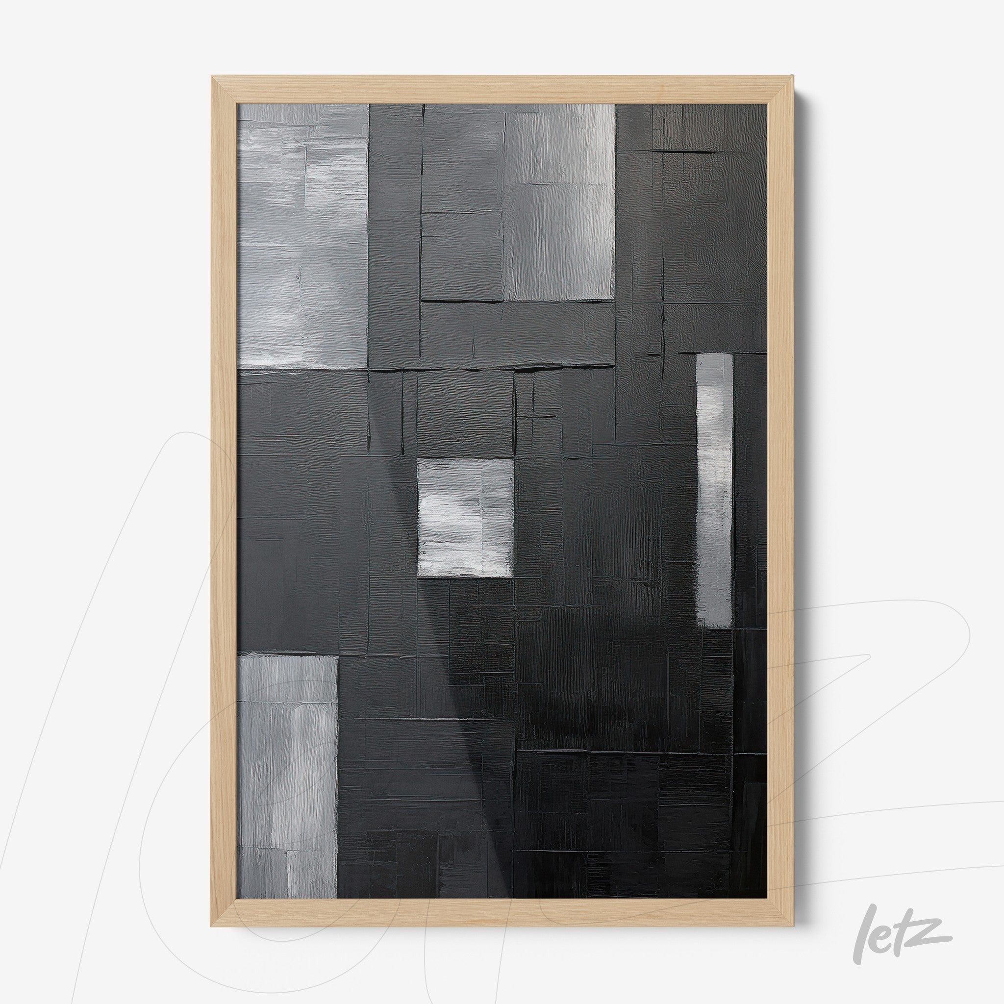 abstract wall art in shades of black, gray, and white with a light wood frame