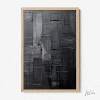 abstract wall art in shades of black and gray presented in a light wood frame