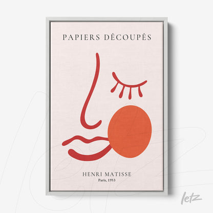 framed wall art featuring minimalist drawing of a face in red and pink tones with silver frame