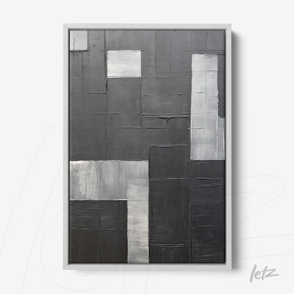 abstract wall art in shades of black and gray with varied textures in white frame