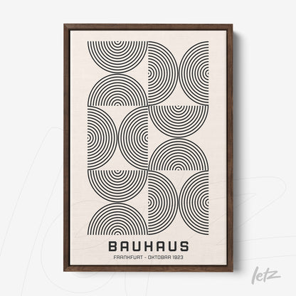 framed wall art featuring black concentric circles on a white background with a dark wood frame