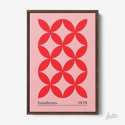 framed artwork with red geometric pattern on pink background, text bauhaus 1919, dark wood frame