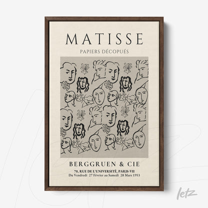 framed wall art featuring modern style black and white faces against a light background with dark wooden frame