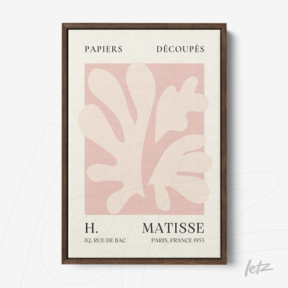 framed wall art featuring paper cutouts in shades of pink and cream with dark wood frame