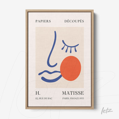 framed contemporary art print featuring an abstract face design with colorful shapes in a light wood frame