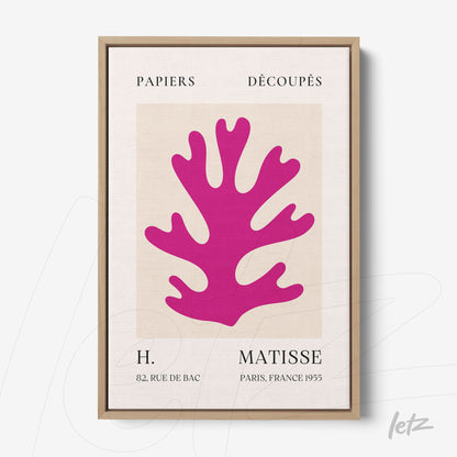 canvas wall art featuring colorful cutout design in pink, framed in light wood with neutral background