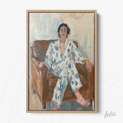framed artwork of a woman sitting on a brown sofa, wearing a blue and white patterned pajama, light wooden frame