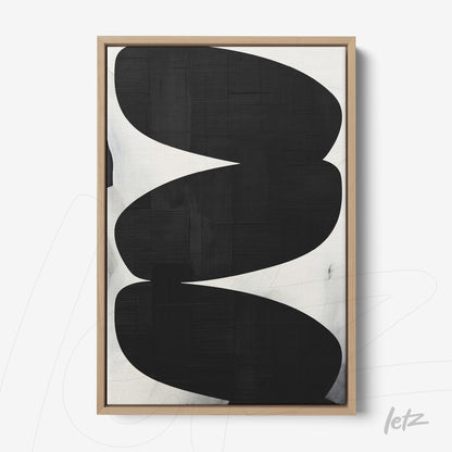 abstract wall art with black organic shapes on light background framed in light wood