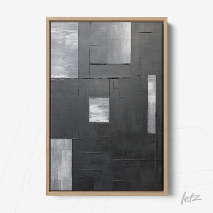 abstract wall art in black and gray with textured rectangles on a uniform background, framed in light wood