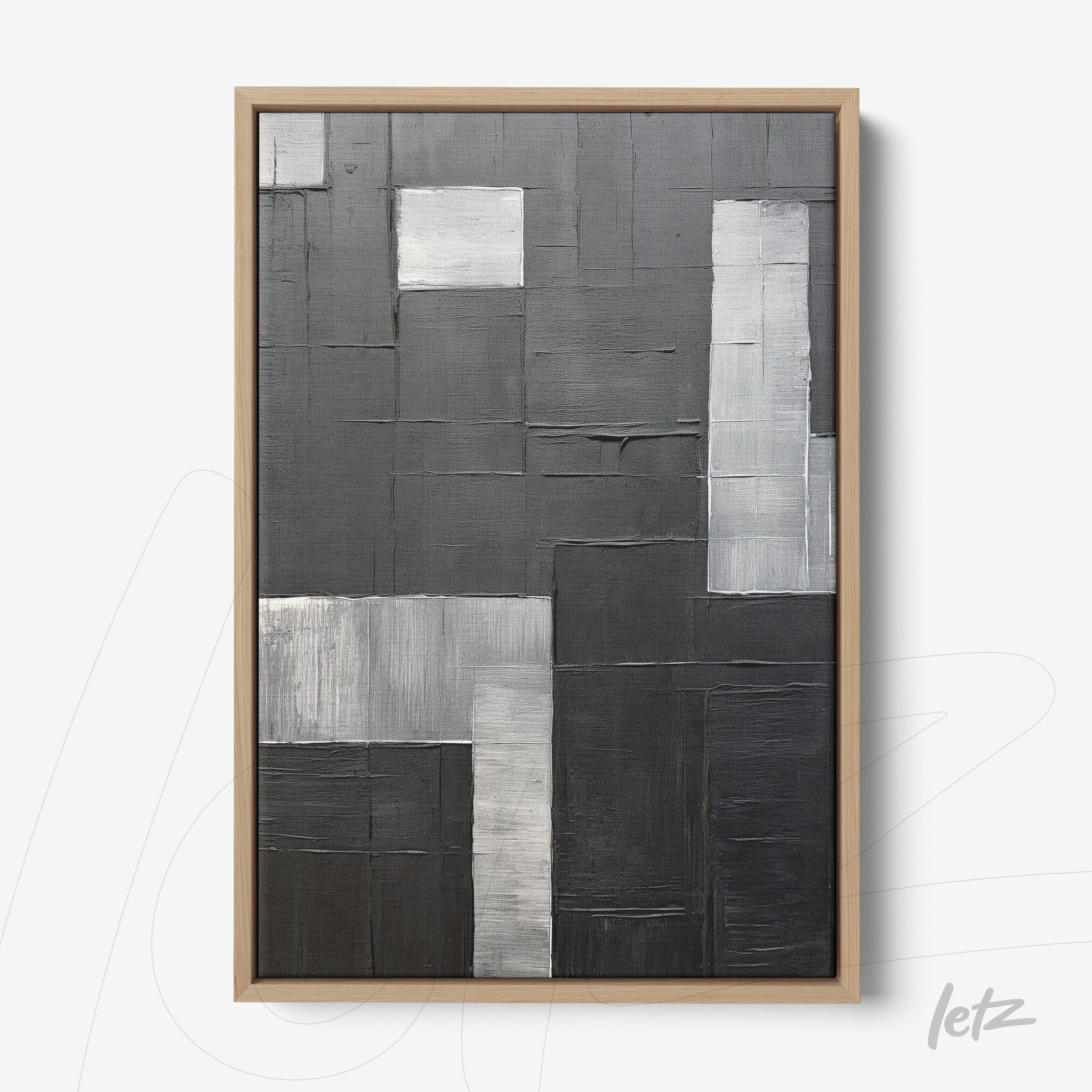abstract wall art in shades of black and gray with bold texture, framed in light wood