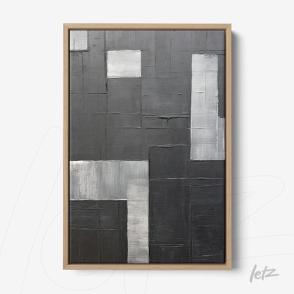 abstract wall art in shades of black and gray with bold texture, framed in light wood