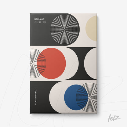 canvas art featuring Bauhaus style geometric design in black, red, blue, and beige with concentric circles and abstract shapes displayed on a white wall