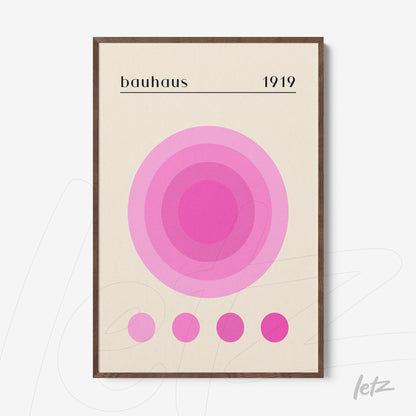 framed wall art with concentric circles in shades of pink and text bauhaus 1919 in wooden frame