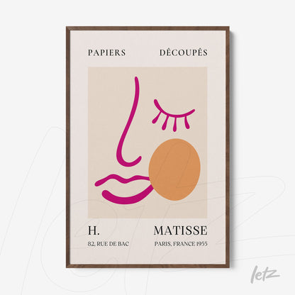 framed wall art featuring minimalist illustration on light background with pink and orange lines forming a stylized face, dark wooden frame