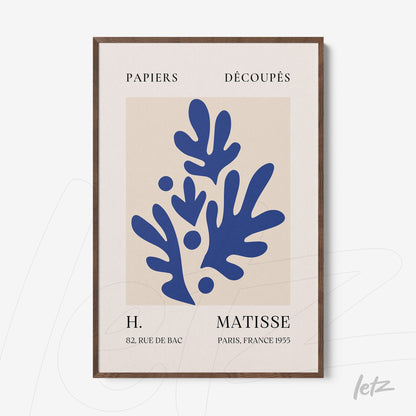 framed art of paper cutouts in blue on light background with dark wood frame