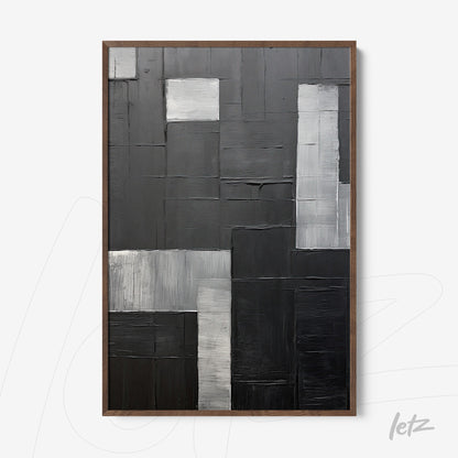 abstract wall art in shades of black and gray with varied textures in light wooden frame