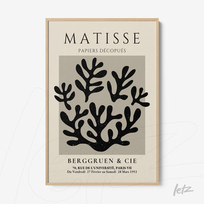 framed wall art featuring black and white cut-out leaves with a light wood frame