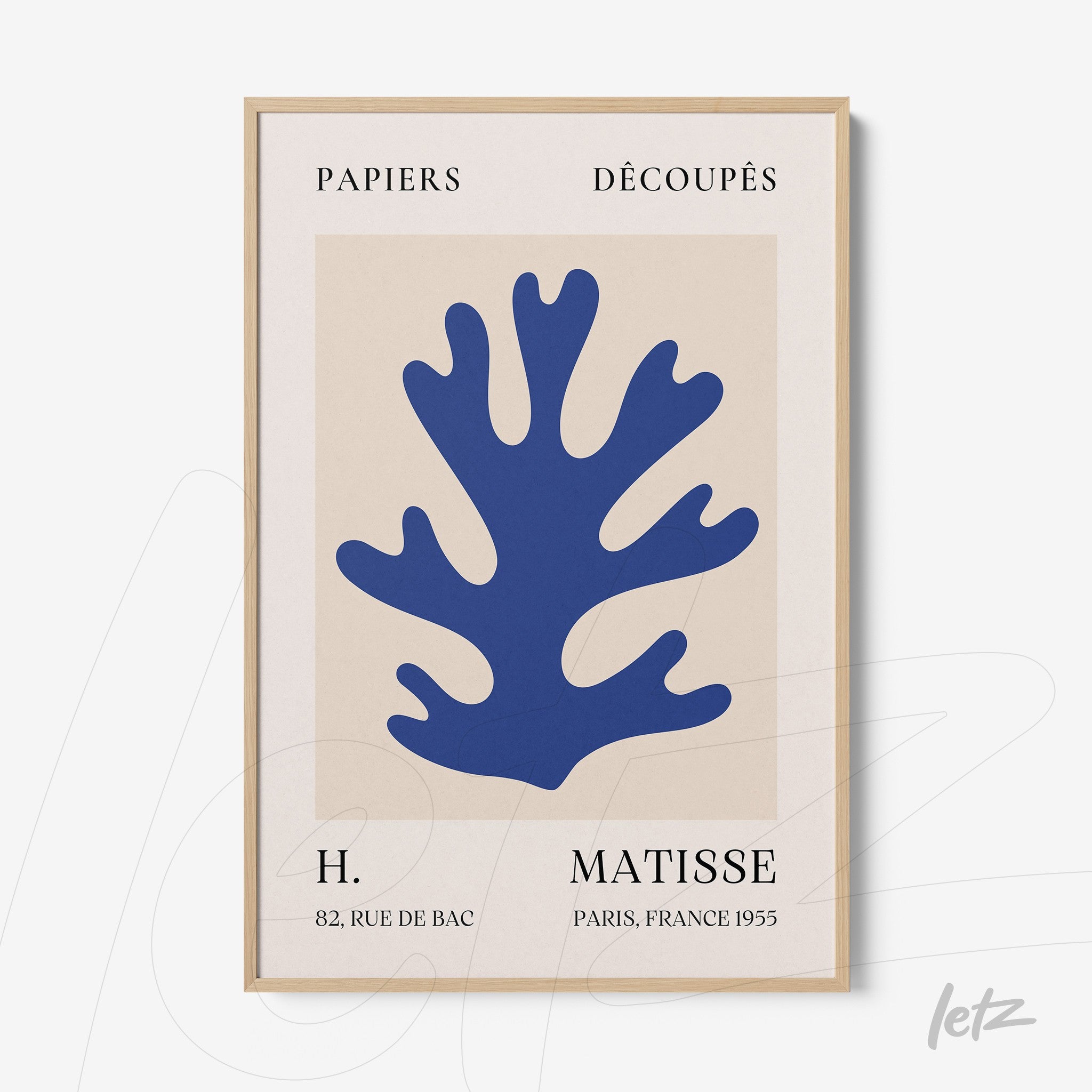 framed art featuring blue paper cutouts, light wood frame, neutral background, and stylish text