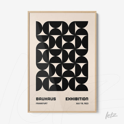 framed artwork featuring black geometric pattern and text about bauhaus exhibition with light wood frame