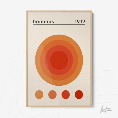 poster print featuring concentric circles in shades of orange and red with the text bauhaus 1919 displayed in a light wood frame