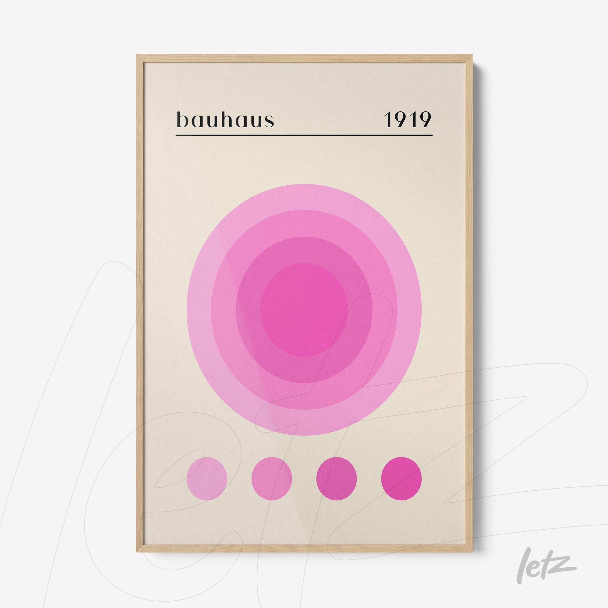 geometric art print in shades of pink with 'bauhaus 1919' text and light wood frame