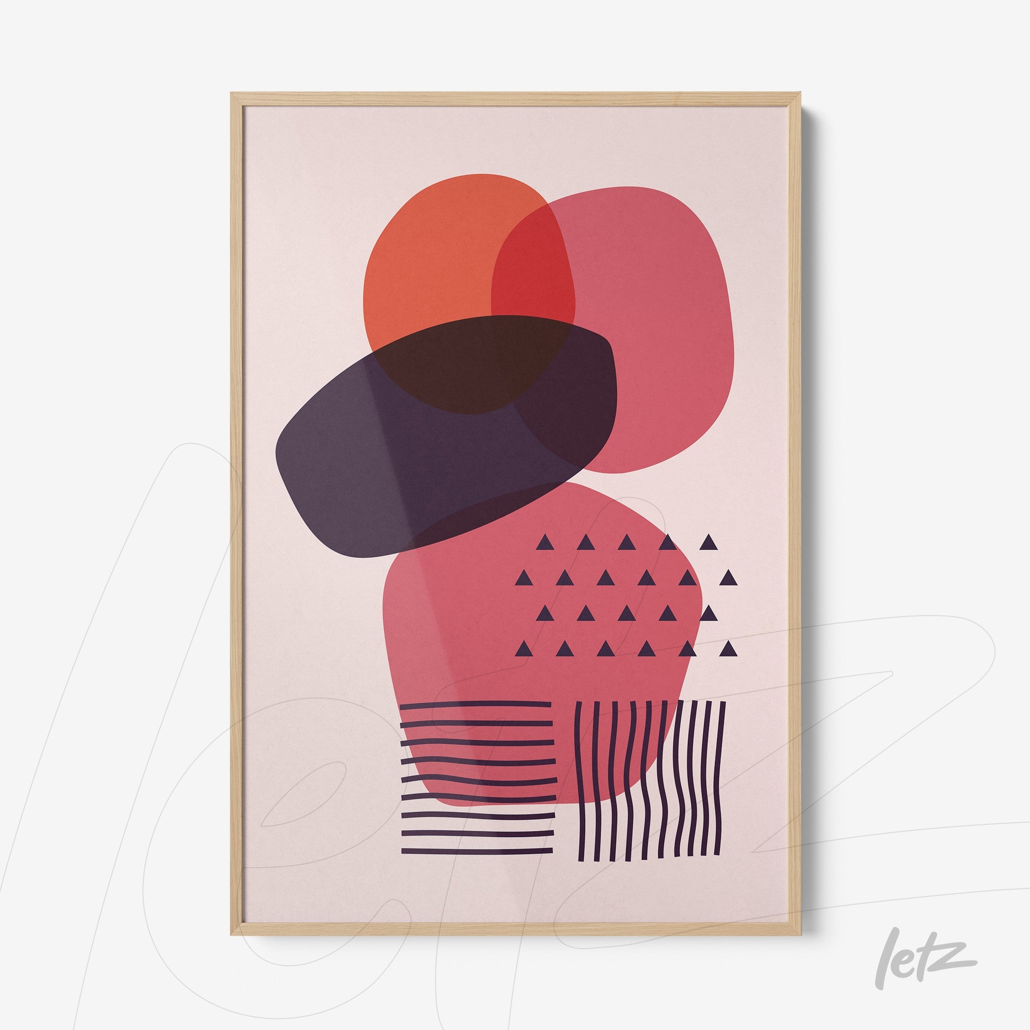 poster featuring abstract geometric shapes in pink, red, and purple tones, framed with light wood