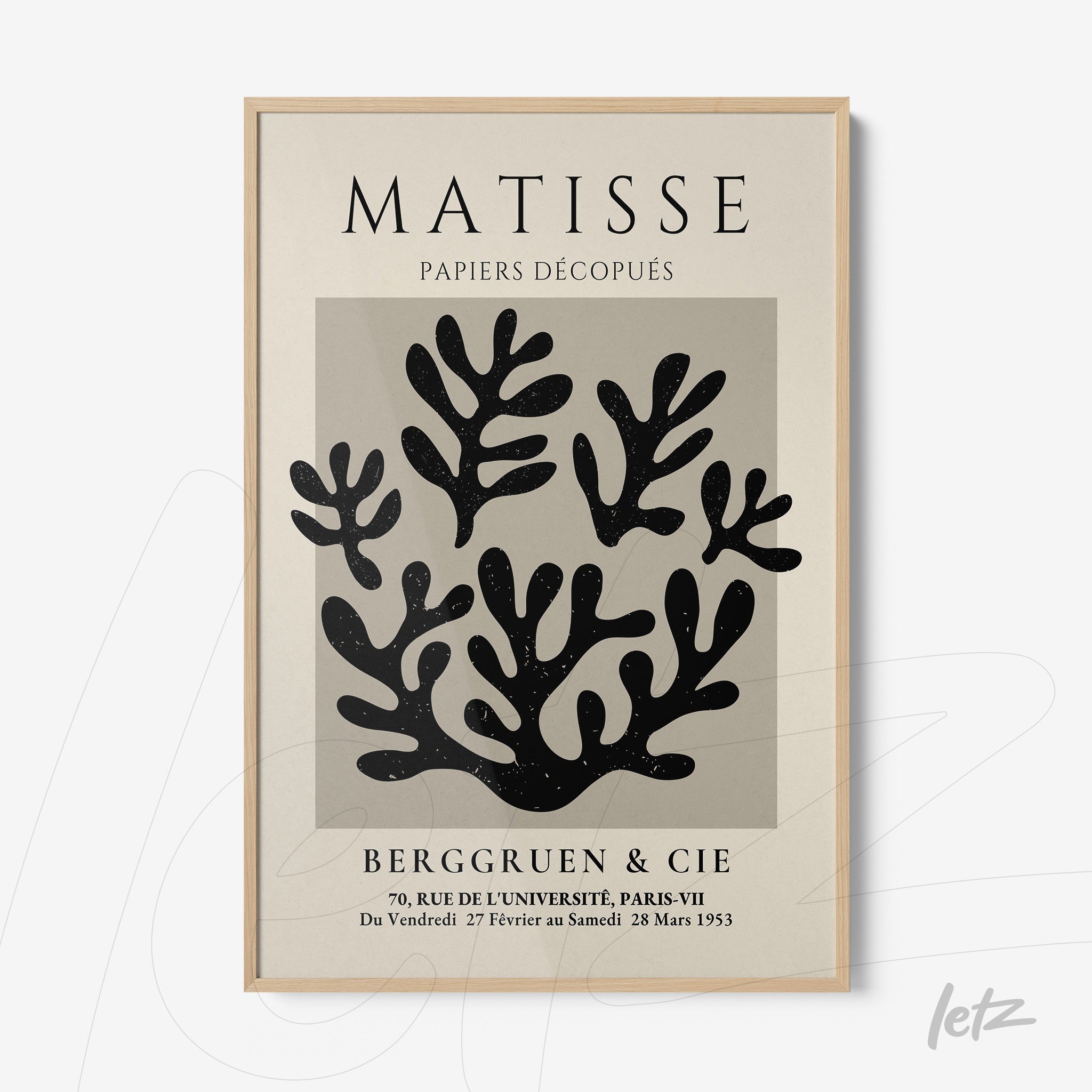 framed wall art featuring abstract black cutouts on a cream background with light wood frame