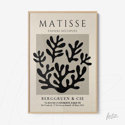 framed wall art featuring abstract black cutouts on a cream background with light wood frame