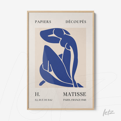 framed wall art featuring a blue illustration of a female figure on a light background with light wood frame